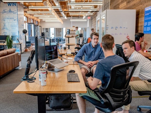 Three men talking in a coworking space