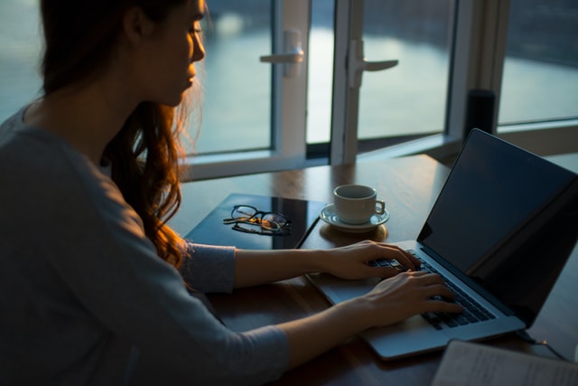 A woman working on her laptop at sunset.