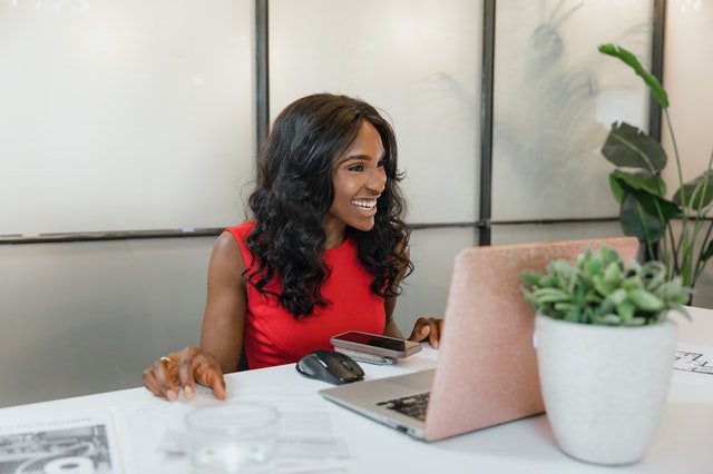 Woman in a red dress working at her desk.