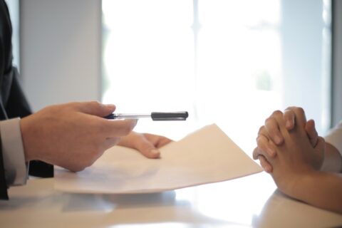 Man handing over contract and pen to a client.