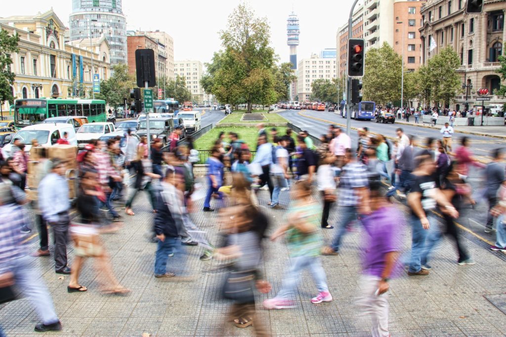 A large group of people crossing a sidewalk.