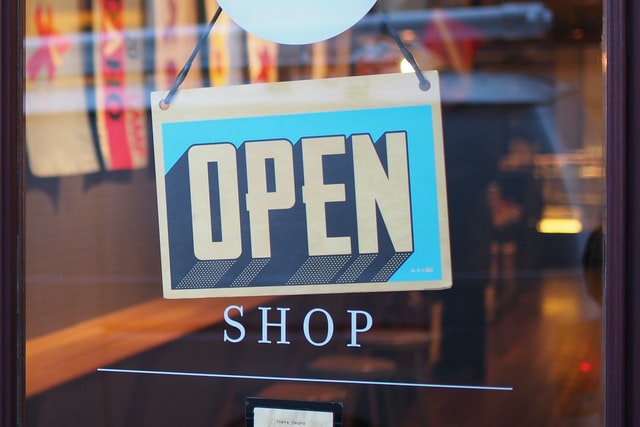 An Open Shop sign hanging on shop doors after renting retail space in San Diego.